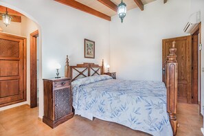 A bedroom with a bed, wooden furniture, a painting on the wall, and a ceiling fan. - Single-Level Villa with Pool, Pollença (Pollensa / Pollença)