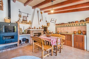 A rustic kitchen with a stone fireplace, wooden furniture, and traditional cookware. - Single-Level Villa with Pool, Pollença (Pollensa / Pollença)