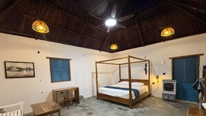 Une chambre dotée d’un lit à baldaquin, d’un bureau, d’une chaise, d’une table et d’un ventilateur de plafond.