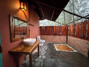 Ein Badezimmer mit einer Holzbank, einem gro ßen Spiegel, einem Waschbecken und einer Toilette.