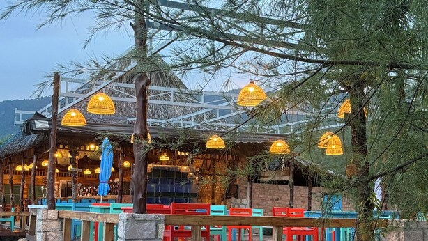 Un restaurant doté d’une terrasse, de piliers en pierre et de lampes suspendues.