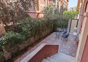 Un quartier résidentiel avec un escalier menant à un espace extérieur abrité, aménagé avec deux chaises et une table.