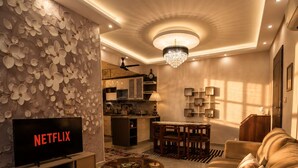 Una sala de estar moderna con televisión, sofá, mesa de centro y decoración en la pared.