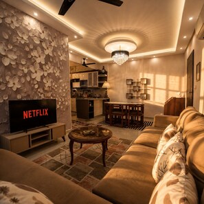 Een moderne woonkamer met een televisie, bank, salontafel en decoratieve wand.