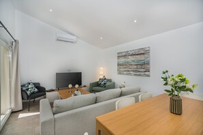 A modern living room with a sofa, a dining table, a TV, and a painting on the wall. - Premium Pollensa Country Villa for 6 (Pollensa)
