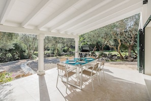 An outdoor patio with a table and chairs, a grill, and a view of trees and rocks. - Premium Pollensa Country Villa for 6 (Pollensa)