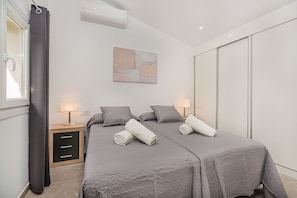 A modern bedroom with two beds, bedside lamps, a wall-mounted air conditioner, and a large abstract painting. - Premium Pollensa Country Villa for 6 (Pollensa)
