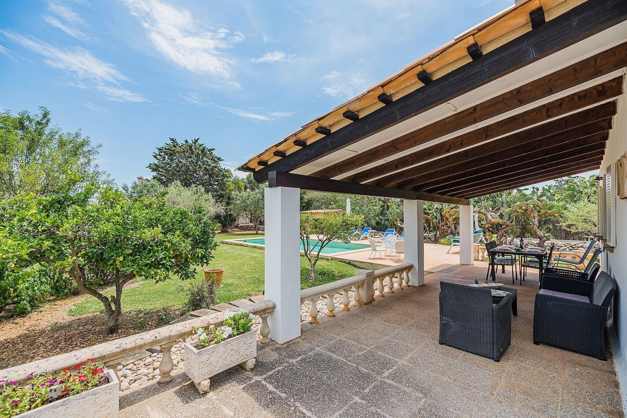 A covered outdoor patio with a pool, seating area, and garden.