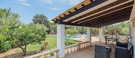 A covered outdoor patio with a pool, seating area, and garden.