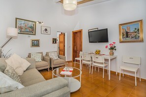 A living room with a sofa, armchairs, a coffee table, a TV, and artwork on the walls. - Romantic Pollensa Country Escape (Pollensa / Pollença)