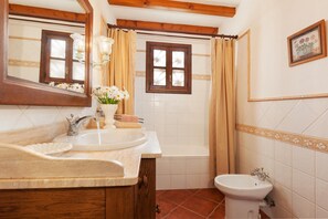 Ein Badezimmer mit Waschbecken, Spiegel, Fenster und Dusche.