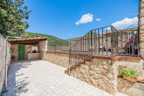 Ein Außenbereich mit Steinsäulen und einer Metalltreppe zu einer überdachten Terrasse.