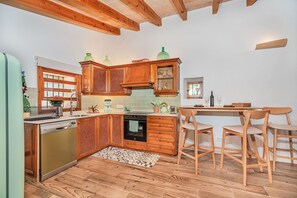 Una cocina con armarios de madera, horno empotrado y un comedor con sillas de madera.