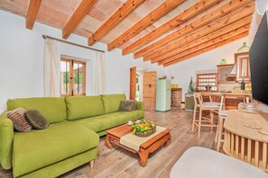 Ein gemütliches Wohnzimmer mit einem grünen Sofa, einem Holztisch und einem Essbereich mit Tisch und Stühlen.