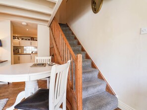 Eine Treppe mit Holzgeländern führt zu einem Küchenbereich mit Schr änken und einem Esstisch.