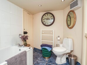 Ein Badezimmer mit einer Badewanne, Toilette und einer Wanduhr.