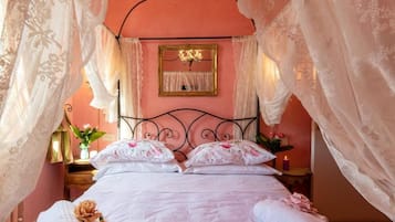 A bed with a canopy, a bedside table with a lamp, and a mirror on the wall.