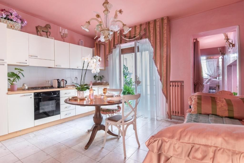 Una stanza in tonalità rosa con un tavolo da pranzo, sedie e un letto.