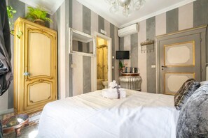 Quarto de hotel com uma cama grande, um guarda-roupa, um espelho, uma televisão e uma porta.