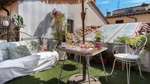 Eine Terrasse im Freien mit Esstisch, einer Couch und einem Sessel.