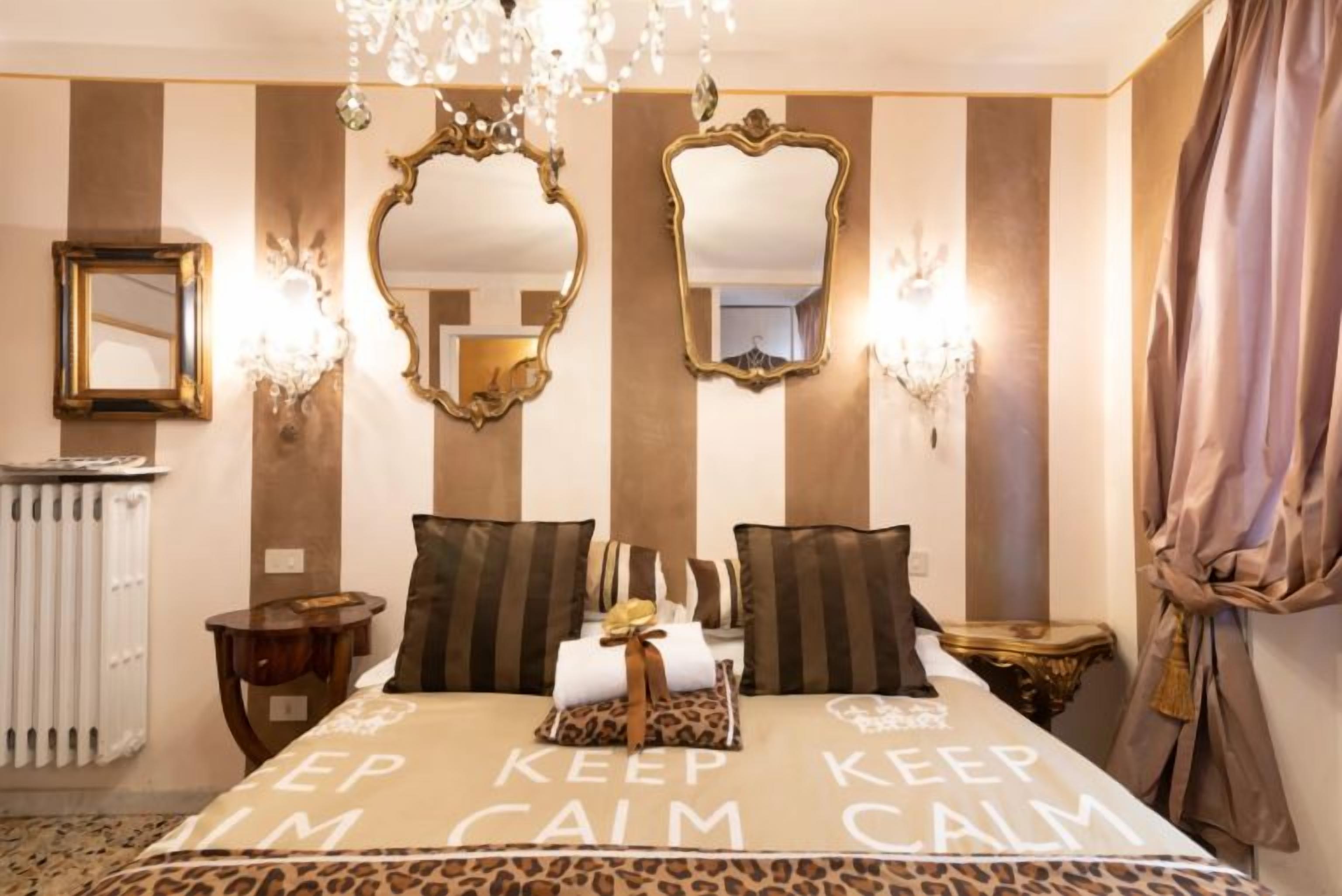 Een hotelkamer met een bed, twee spiegels, een kroonluchter en een radiator.