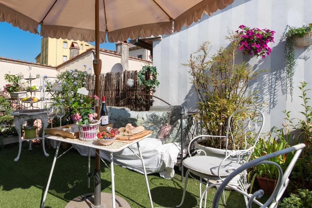 Eine Terrassenanlage im Freien mit Tisch, Stühlen und verschiedenen Kübelpflanzen.