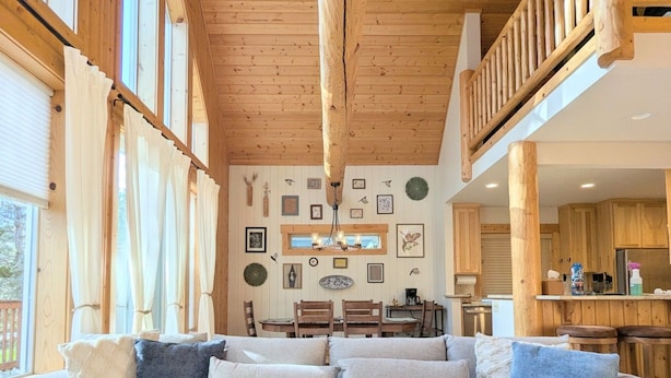 A cozy living room with a sectional sofa, wooden beams, and a dining area in the background. - Sage Creek Chalet At The Running Y (Klamath Falls)