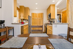 Une cuisine moderne avec des meubles en bois, un îlot central et un coin repas comprenant deux chaises et une table.