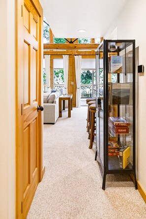A hallway leading to a seating area with a glass display case containing books and games.