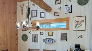 A wooden dining room with a round table, chairs, and a hanging light fixture. - Sage Creek Chalet At The Running Y (Klamath Falls)