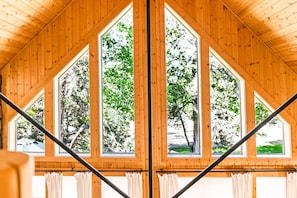 A room with a wooden ceiling and large windows.