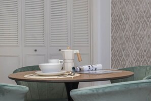 Une table ronde avec une théière blanche, des tasses et un menu enroulé.