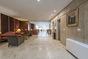 A hotel lobby with a reception desk, seating area, and a large window providing a view of the outdoors. - CIty Central Flat in Madrid for 4 (Madrid)