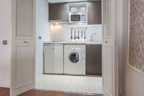 A compact kitchen with a microwave, sink, and washing machine. - CIty Central Flat in Madrid for 4 (Madrid)
