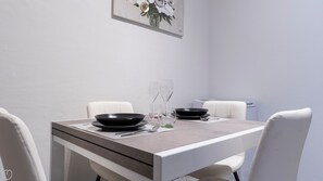 Una taula de dinar amb bols negres, gots transparents i una cadira blanca.