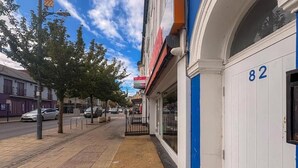 A sidewalk next to a building with a blue door and the number 82. - Prince Of Wales Rd - Apartment 1 (Norwich)