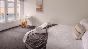 A hotel room with a bed, a desk, a chair, and a window. - Prince Of Wales Rd - Apartment 1 (Norwich)