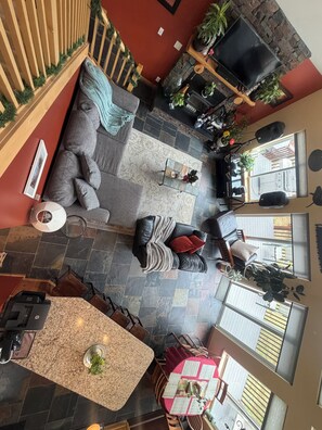 Un vaste espace de vie doté d’un sol en pierre, d’une cheminée, d’un grand canapé et d’une table à manger avec des chaises.