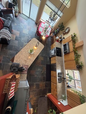Une cuisine spacieuse dotée d’un plan de travail en pierre, de meubles de rangement en bois et d’un coin repas avec une nappe rouge.