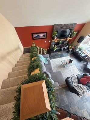 A staircase leading to a living area with a fireplace, a television, and various plants. - The Rock House of Herron Island (Home)