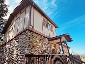 Une maison à deux étages avec une façade en pierre et un balcon en bois.