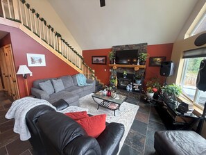 Un salon avec une cheminée, un canapé, une table basse et un escalier doté d’une rampe.