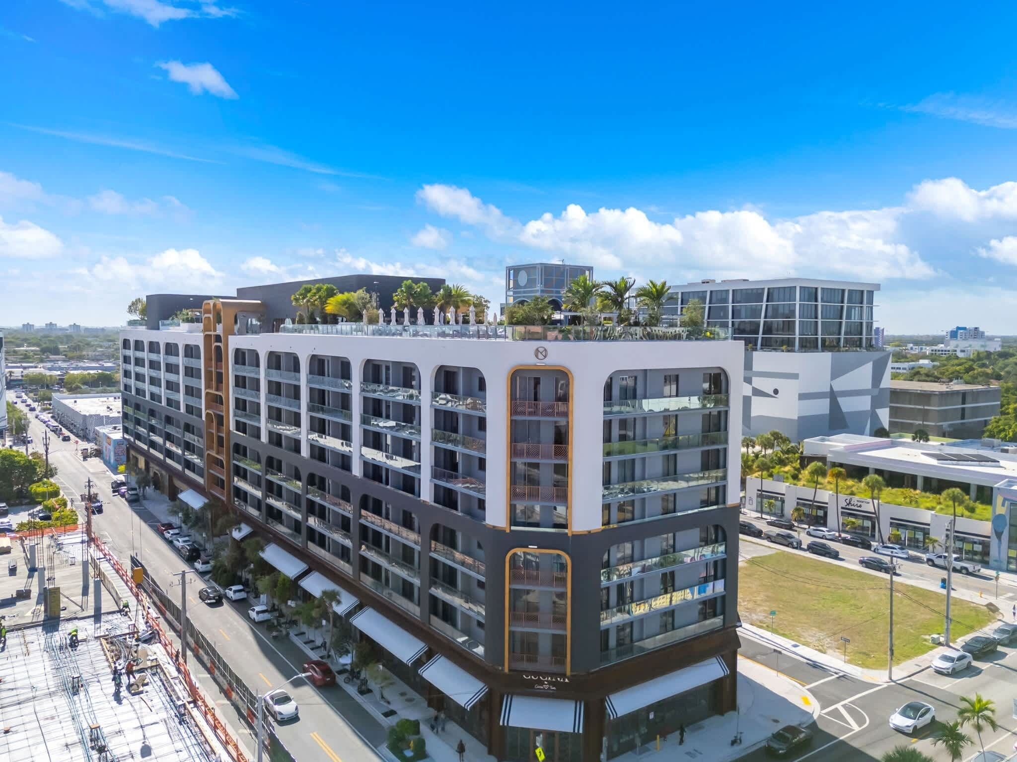 A multi-story hotel with a modern architectural design, featuring balconies and a rooftop garden.