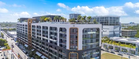 Un hôtel à plusieurs étages doté d’une architecture moderne, avec des balcons et un jardin sur le toit.