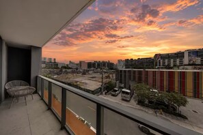 Een balkon met uitzicht op een zonsondergang boven een stadsgezicht, inclusief gebouwen en bouwplaatsen.