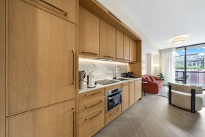 A modern kitchen with wooden cabinets, a built-in oven, and a large window. - Vibrant Wynwood Condo & Resort (Miami)