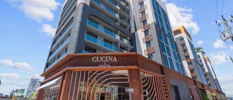 A multi-story hotel with a modern design, featuring a prominent entrance with a sign reading 'CUCINA by Coco & Tua.'