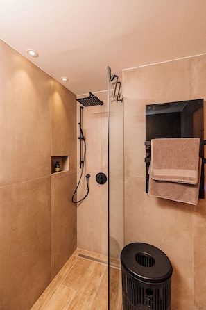 Un bagno moderno con doccia a vetro, un cestino nero e un portasciugamani con asciugamani.