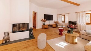 A modern living room with a fireplace, wooden flooring, a flat-screen TV, and a sofa. - Haute Alpine Living (S-chanf)