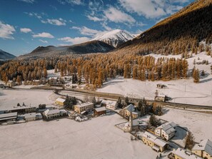 Une ville enneigée, avec des bâtiments, une église et une montagne en arrière-plan.